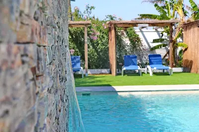 a pool with blue chairs and a gazebo at Bungalow La Roa I in Conil de la Frontera