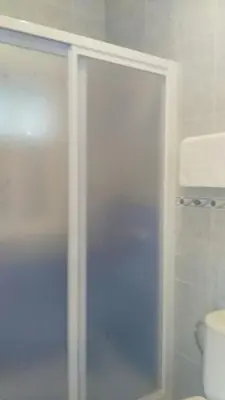 a glass shower in a bathroom with a toilet at Hostal las Parcelas in Conil de la Frontera