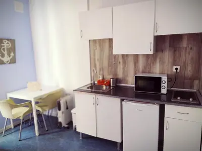a kitchen with white cabinets and a table and a microwave at Spanish Galleon Lodge in Cádiz