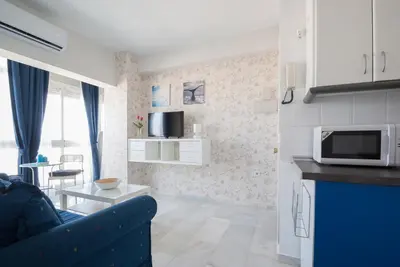 a living room with a blue couch and a microwave at Apartment Altavista in Cádiz