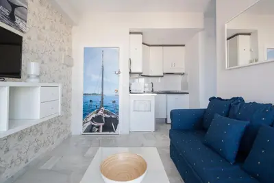 a living room with a blue couch and a kitchen at Apartment Altavista in Cádiz