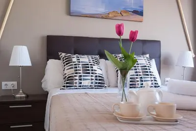 a bedroom with a bed with a vase with pink flowers at Apartment Altavista in Cádiz
