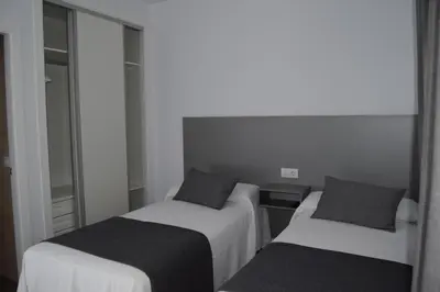 two beds in a small room with mirrors at Alojamientos Alma in Conil de la Frontera