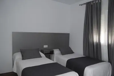 a hotel room with two beds and a window at Alojamientos Alma in Conil de la Frontera