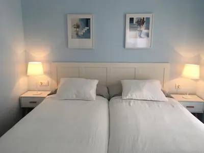 two beds in a bedroom with two lamps on both sides at Apartamento Cantabrico in Cádiz