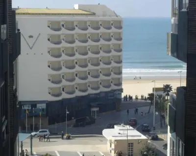 a large building on a beach next to the ocean at Apartamento Cantabrico in Cádiz
