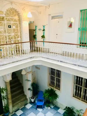 a hallway of a building with a staircase and a blue chair at Pensión Cádiz in Cádiz