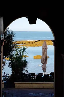 an umbrella and a table and chairs and a body of water at Apartamento Playa Muralla in El Puerto de Santa María