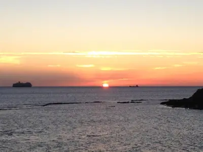 a sunset on the beach with the sun setting at Apartamento Playa Muralla in El Puerto de Santa María