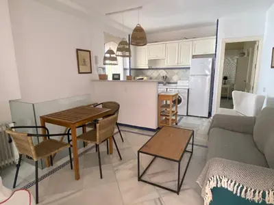 a kitchen and a living room with a table and chairs at Apartamento Playa Muralla in El Puerto de Santa María