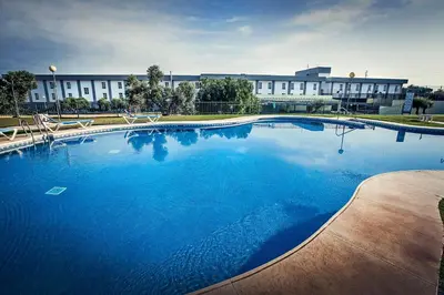 a large blue swimming pool in front of a building at Gran Hotel Ciudad Del Sur in Puerto Real