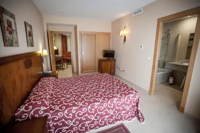 a bedroom with a red and white bed and a bathroom at Gran Hotel Ciudad Del Sur in Puerto Real