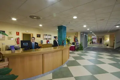 two men sitting at a reception desk in a lobby at Gran Hotel Ciudad Del Sur in Puerto Real