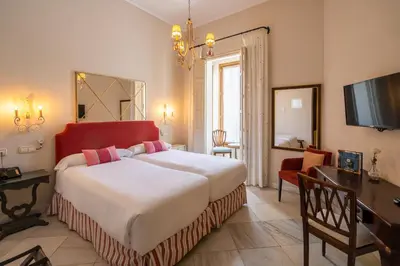 a bedroom with a large bed and a desk and a television at Hotel YIT Casa Grande in Jerez de la Frontera