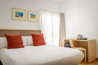 a bedroom with a large white bed with orange pillows at BYPILLOW Tiento in Cádiz