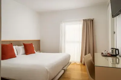 a bedroom with a large white bed and a window at BYPILLOW Tiento in Cádiz