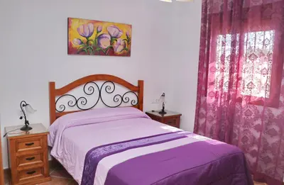 a bedroom with a bed with purple sheets and a window at Chalet Vigía 114 in Conil de la Frontera