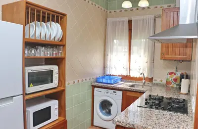 a kitchen with a washing machine and a microwave at Chalet Vigía 114 in Conil de la Frontera