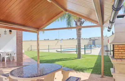 a patio with a table and a palm tree at Chalet Vigía 114 in Conil de la Frontera