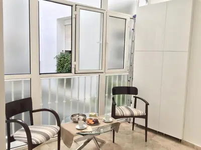 a room with two chairs and a table and windows at Apartamento San Pedro in Cádiz