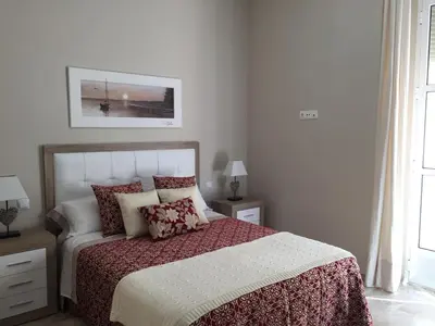 a bedroom with a large bed with red and white sheets at Apartamento San Pedro in Cádiz