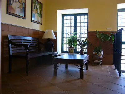 a living room with a table and a bench and windows at Mesón de la Molinera in Arcos de la Frontera