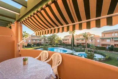 a balcony with a table and chairs and a swimming pool at Apartamento Mijares in Chiclana de la Frontera