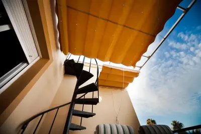 a balcony with stairs and a yellow umbrella at Ático Barrio de los Pescadores in Costa Ballena