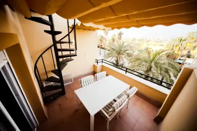 a balcony with a table and chairs and a staircase at Ático Barrio de los Pescadores in Costa Ballena