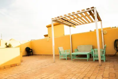 a patio with chairs and a pergola on a house at Ático Barrio de los Pescadores in Costa Ballena