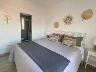 a bedroom with a large white bed with orange pillows at Atico Infanta Eulalia in Sanlúcar de Barrameda