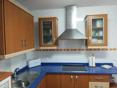 a kitchen with a blue counter top and wooden cabinets at Atico Infanta Eulalia in Sanlúcar de Barrameda