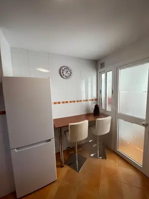 a kitchen with a table and chairs and a clock on the wall at Atico Infanta Eulalia in Sanlúcar de Barrameda