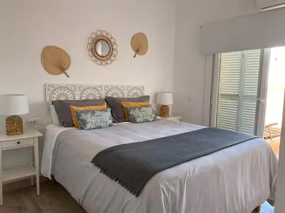 a bedroom with a large bed and a mirror on the wall at Atico Infanta Eulalia in Sanlúcar de Barrameda