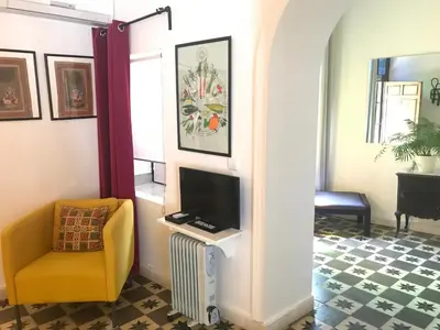 a living room with a tv and a yellow chair at Casa Seven Jerez in Jerez de la Frontera