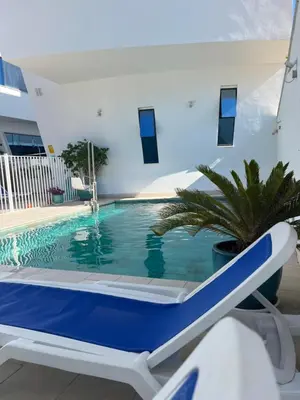 a blue and white swimming pool with a chair next to a house at Ancla Real Apartamentos Loft in El Puerto de Santa María