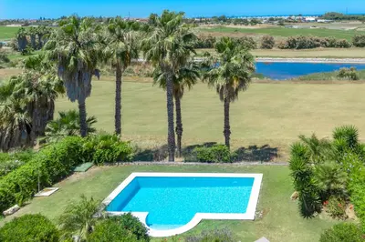 an overhead view of a swimming pool and palm trees at Villa Golf Sanlucar in Sanlúcar de Barrameda