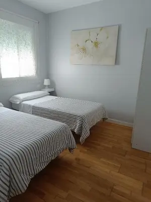 two beds in a room with white walls and wooden floors at Apartamentos Aloha 2 Centro El Puerto de Santa Maria in El Puerto de Santa María