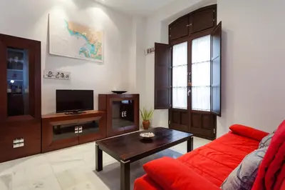 a living room with a red couch and a tv at Casa ALEGRIA by Cadiz4Rentals in Cádiz