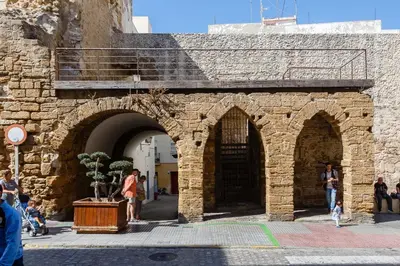 a stone building with arches and people walking around at Casa ALEGRIA by Cadiz4Rentals in Cádiz