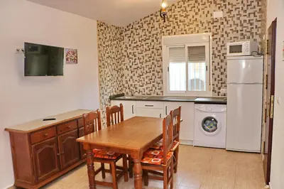 a kitchen with a wooden table and a refrigerator at Chalet La Roa III in Conil de la Frontera