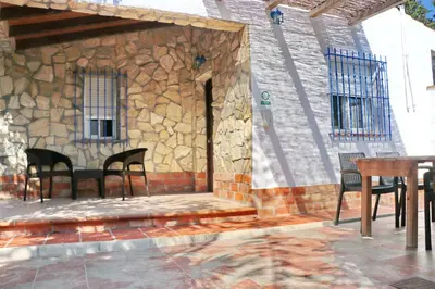 a patio with chairs and a stone wall at Chalet La Roa III in Conil de la Frontera