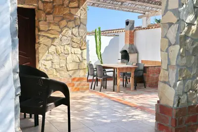 a patio with a table and chairs and a stone wall at Chalet La Roa III in Conil de la Frontera