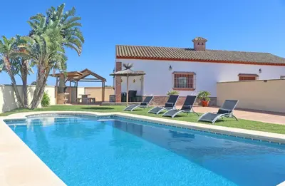 a swimming pool with two chairs and a house at Chalet Vigía 113 in Conil de la Frontera