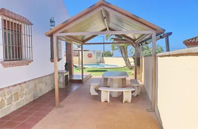 a wooden pavilion with a table and benches on a patio at Chalet Vigía 113 in Conil de la Frontera