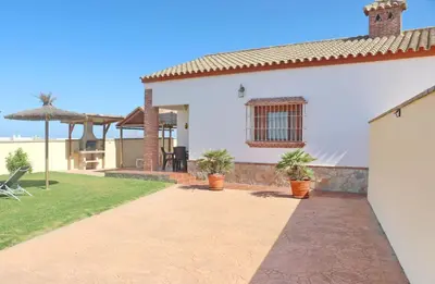 a white house with potted plants in a yard at Chalet Vigía 113 in Conil de la Frontera