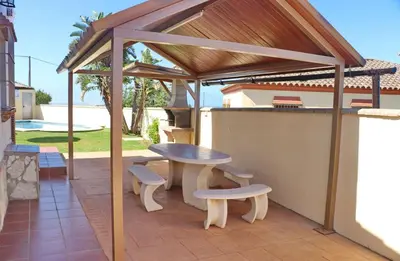 a wooden pavilion with a table and benches on a patio at Chalet Vigía 113 in Conil de la Frontera