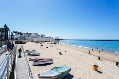 a beach with boats and people in the water at Apartamento La PALMA free parking by Cadiz4Rentals in Cádiz