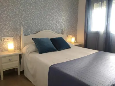 a bedroom with a white bed and two night stands with lamps at Apartamento Fernández Ladreda in Cádiz