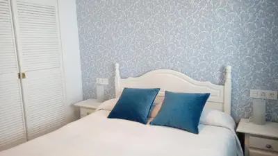 a bedroom with a white bed with blue walls at Apartamento Fernández Ladreda in Cádiz